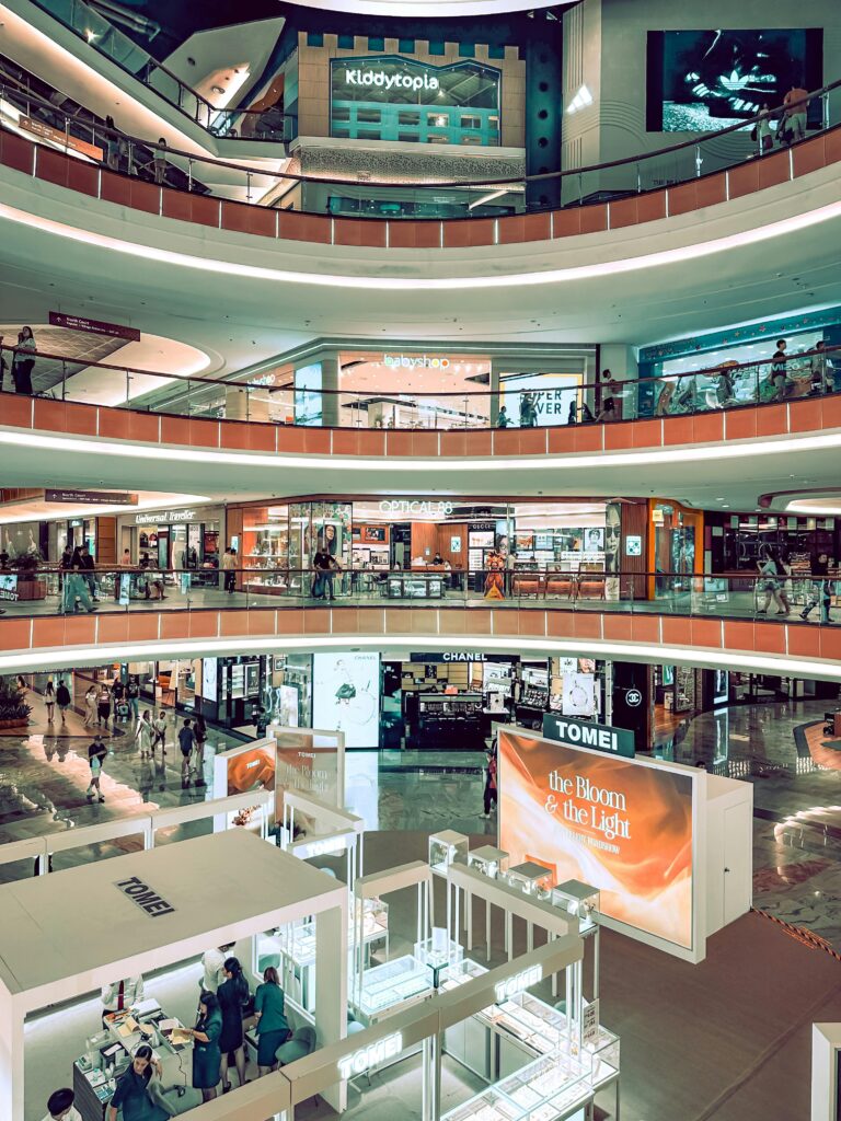 Four levels of a bustling modern shopping mall with various retail stores.